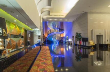 Manhattan Hotel lobby with spiral staircase. Gay-friendly hotel design with modern decor, reception desk, and polished floors. Upscale travel experience.