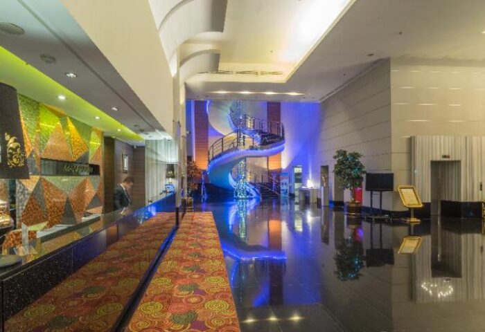 Manhattan Hotel lobby with spiral staircase. Gay-friendly hotel design with modern decor, reception desk, and polished floors. Upscale travel experience.