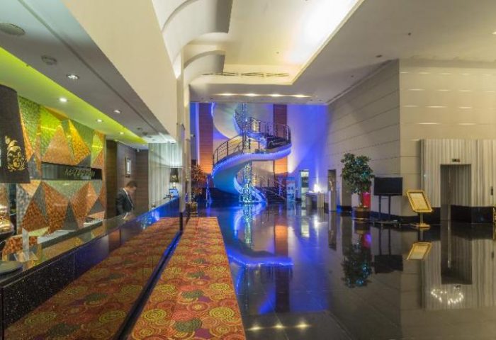 Manhattan Hotel lobby with spiral staircase. Gay-friendly hotel design with modern decor, reception desk, and polished floors. Upscale travel experience.