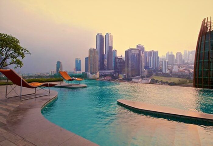 Manhattan Hotel's rooftop pool with city view. Gay-friendly hotel offers luxury with skyline views. Loungers by the infinity pool.