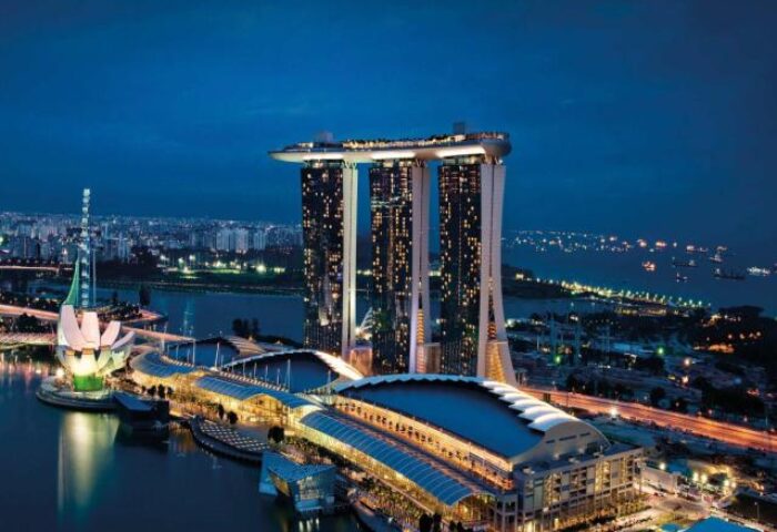 Night view of Marina Bay Sands, a gay-friendly hotel in Singapore. The iconic towers and lotus-shaped ArtScience Museum are illuminated.