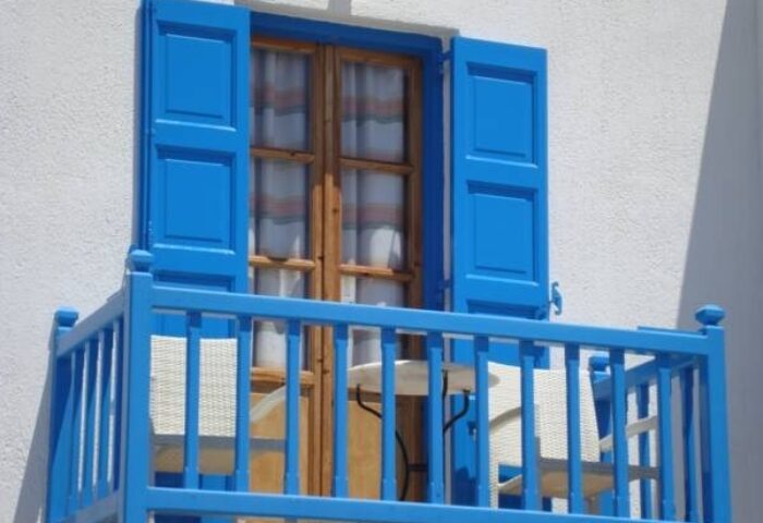 Marina Blue Ornos hotel balcony with blue railings and shutters. Gay-friendly hotel in Mykonos, Greece for gay men's travel.