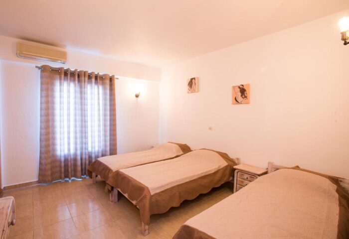 Marina Blue Ornos gay-friendly hotel room. Features three single beds, tiled floor, and simple decor. Ideal for gay men traveling to Mykonos.