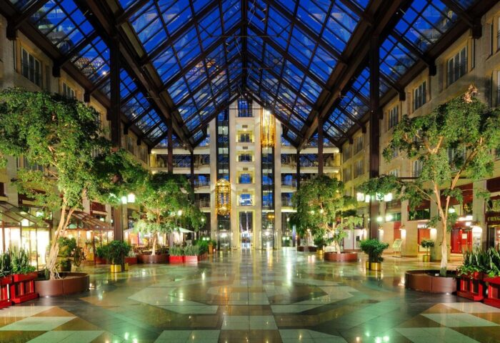 Maritim Hotel Koeln's atrium, a gay-friendly hotel. The interior features a glass ceiling, trees, and a spacious lobby. #gaytravel #cologne