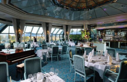 Elegant dining room at gay-friendly Maritim Hotel Koeln. Tables set, piano, and bar area. A great choice for gay travelers in Cologne.