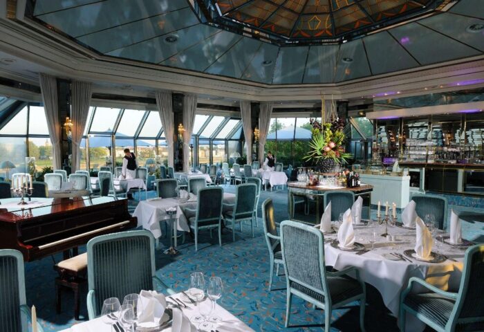 Elegant dining room at gay-friendly Maritim Hotel Koeln. Tables set, piano, and bar area. A great choice for gay travelers in Cologne.