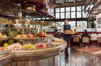 Maritim Hotel Koeln breakfast buffet. Staff member carries bread. Gay-friendly hotel offers diverse food options. Hotel in Cologne, Germany.