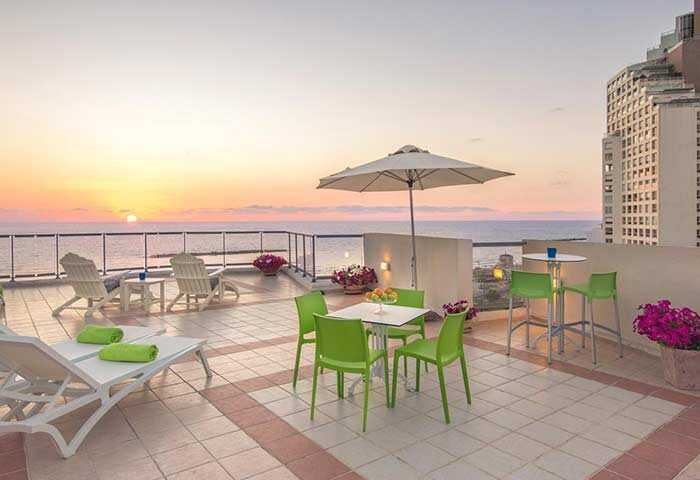 Gay-Friendly Maxim Design Hotel 3 Star Superior terrace view. Tel Aviv hotel with sea view, sun loungers, and seating. Perfect for gay travel.