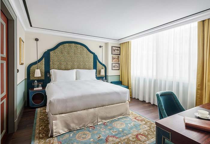 Maxwell Reserve gay-friendly hotel room. Luxurious bed, desk, chair, and rug. Upscale decor for gay travel. Hotel interior design.