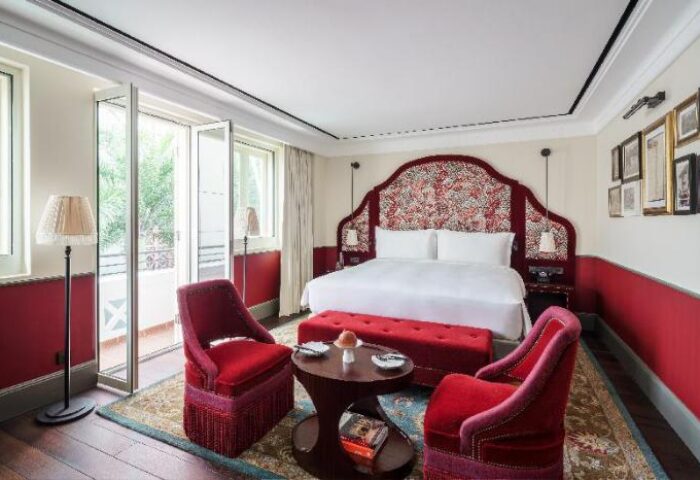 Maxwell Reserve gay-friendly hotel room. Opulent red & white bedroom with balcony, chairs, bed, and stylish decor. Gay travel luxury.