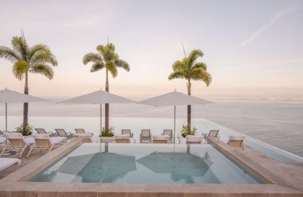 Maxwell Residences at Indah, a gay-friendly hotel. Infinity pool overlooking the ocean. Palm trees and lounge chairs create a relaxing vibe.
