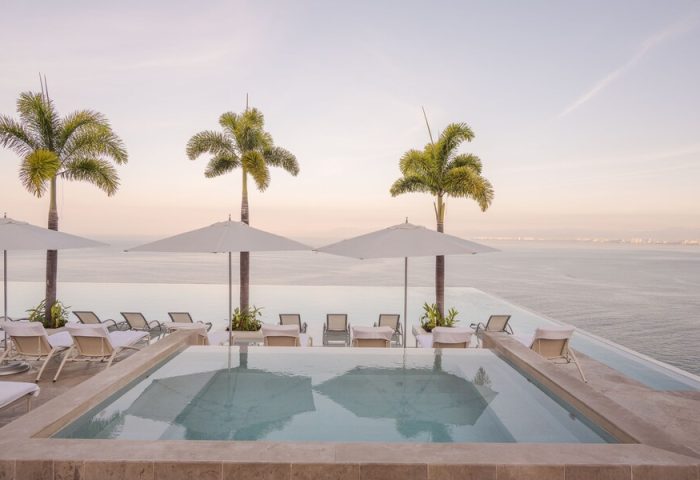 Maxwell Residences at Indah, a gay-friendly hotel. Infinity pool overlooking the ocean. Palm trees and lounge chairs create a relaxing vibe.