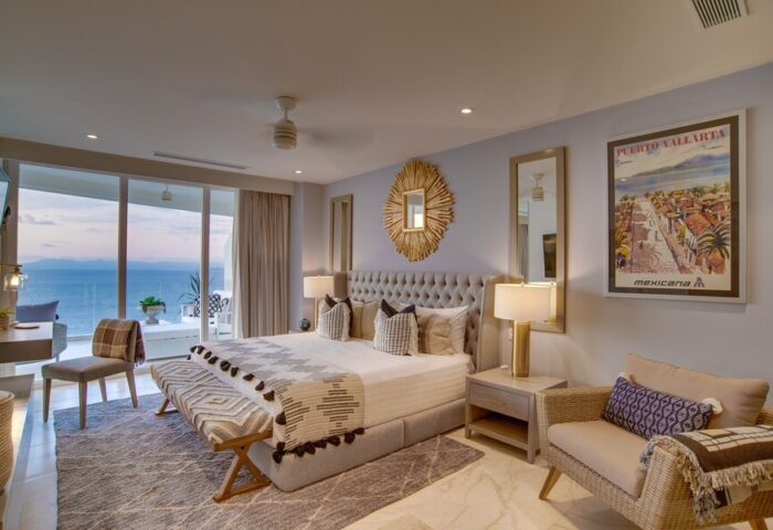 Maxwell Residences at Indah gay-friendly hotel room. Bedroom with king bed, ocean view, balcony, and Puerto Vallarta Mexicana poster.