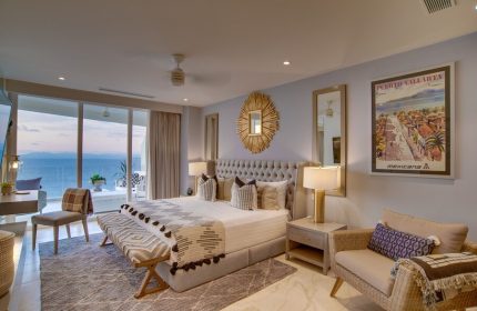 Maxwell Residences at Indah gay-friendly hotel room. Bedroom with king bed, ocean view, balcony, and Puerto Vallarta Mexicana poster.