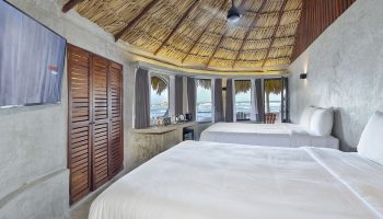 Gay-friendly Maya Tulum By G Hotels room. Two beds, thatched roof, ocean view. Perfect for gay travel and relaxation in Tulum.