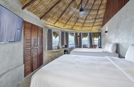Gay-friendly Maya Tulum By G Hotels room. Two beds, thatched roof, ocean view. Perfect for gay travel and relaxation in Tulum.