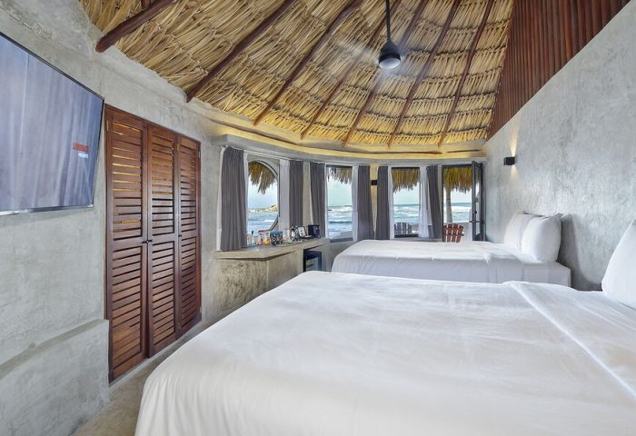 Gay-friendly Maya Tulum By G Hotels room. Two beds, thatched roof, ocean view. Perfect for gay travel and relaxation in Tulum.