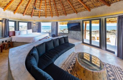 Gay-friendly Maya Tulum By G Hotels suite with thatched roof, ocean view, & stylish decor. Ideal gay travel destination for relaxation.