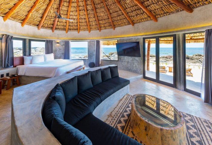 Gay-friendly Maya Tulum By G Hotels suite with thatched roof, ocean view, & stylish decor. Ideal gay travel destination for relaxation.