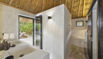 Bathroom at Maya Tulum By G Hotels, a gay-friendly hotel. Thatched roof, concrete walls, and outdoor view. Perfect for gay travel.