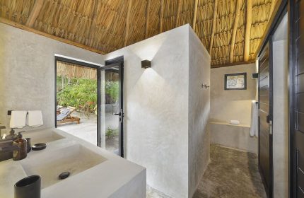 Bathroom at Maya Tulum By G Hotels, a gay-friendly hotel. Thatched roof, concrete walls, and outdoor view. Perfect for gay travel.