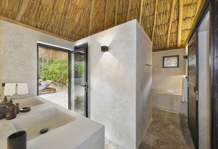 Bathroom at Maya Tulum By G Hotels, a gay-friendly hotel. Thatched roof, concrete walls, and outdoor view. Perfect for gay travel.