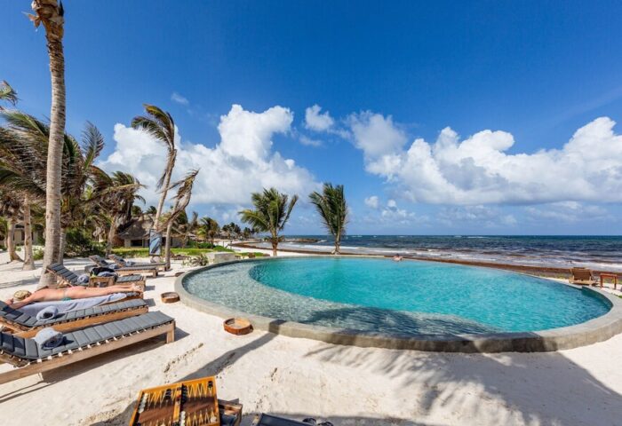 Maya Tulum By G Hotels gay-friendly hotel pool. Beachfront view with palm trees, lounge chairs, and blue skies. Perfect for gay travel.