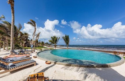 Maya Tulum By G Hotels gay-friendly hotel pool. Beachfront view with palm trees, lounge chairs, and blue skies. Perfect for gay travel.