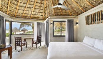 Maya Tulum By G Hotels room. Beach view, thatched roof, white linens. Gay-friendly hotel. Tulum travel for gay men.