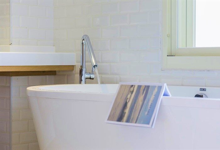 Bathtub detail at Meander Taipei Hostel Ximending. Gay-friendly hotel with modern bathroom, white tile, and stylish fixtures. Relaxing travel lodging.