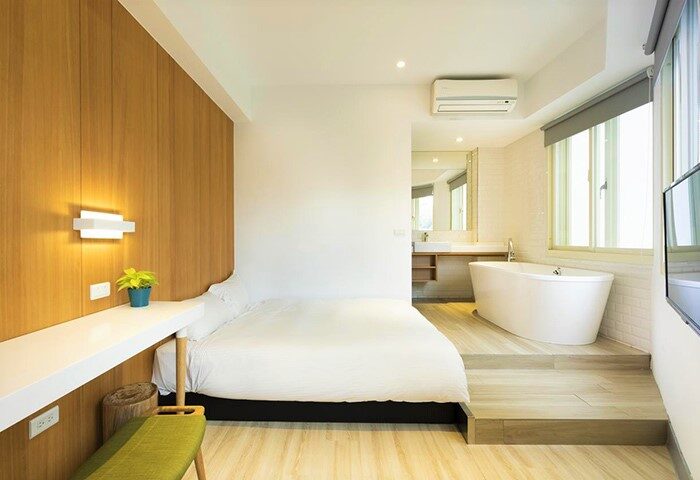 Meander Taipei Hostel Ximending room. Gay-friendly hotel room with bed, desk, and bathtub. Bathroom is adjacent to the bedroom. Taiwan travel.