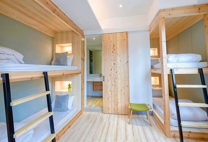 Meander Taipei Hostel Ximending: Gay-friendly hotel with wooden bunk beds, ladders, and a sliding door to the bathroom. Modern hostel room.