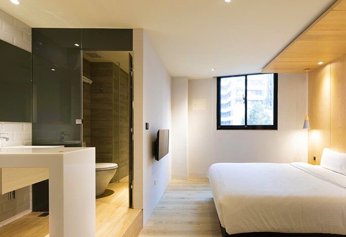 Meander Taipei Hostel Ximending room. Gay-friendly hotel with bed, bathroom, sink, and window. Modern design in Ximending, Taipei for gay travelers.