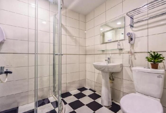 Bathroom at Gay-Friendly Meander Taipei Hostel in Ximending. Shower, sink, toilet, black & white checkered floor. Great for gay travel in Taipei.