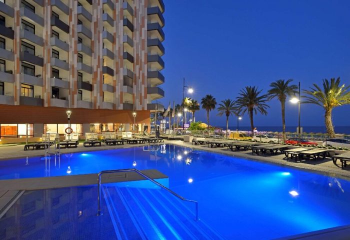Melia Costa del Sol gay-friendly hotel pool at dusk. Palm trees line the beach. A relaxing gay travel destination in Torremolinos, Spain.