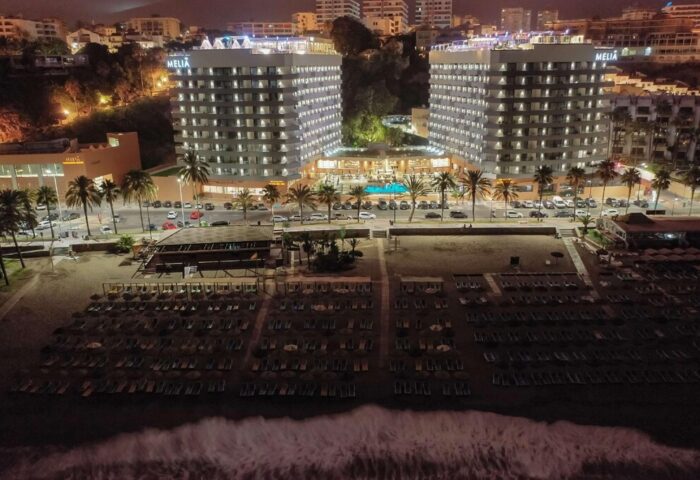 Night view of the gay-friendly Melia Costa del Sol hotel. Beachfront property with pool, palm trees, and beach chairs. Ideal for gay travel.