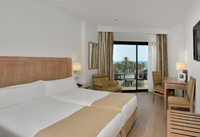 Melia Costa del Sol gay-friendly hotel room. Two beds, desk, chair, and balcony overlooking the beach. Perfect for a relaxing vacation.