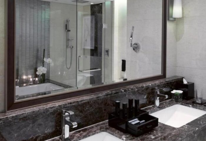 Melia Hanoi Hotel bathroom. Modern design with double sinks, marble countertop, and glass-enclosed shower. Gay-friendly hotel option.