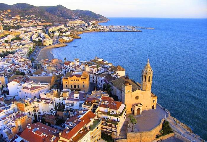 Sitges, Spain aerial view. Gay-friendly travel destination. Beach, marina, and architecture. Melia Sitges hotel nearby. Coastal gay travel.