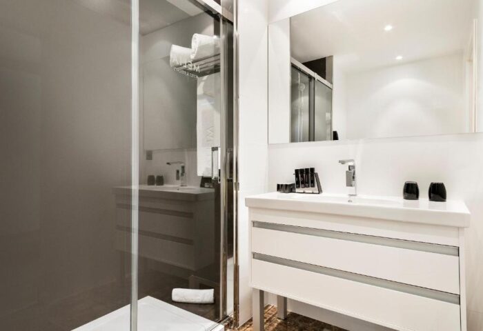 Melia Sitges gay-friendly hotel bathroom. Modern design with a glass shower, white sink, and large mirror. Great for gay travel.