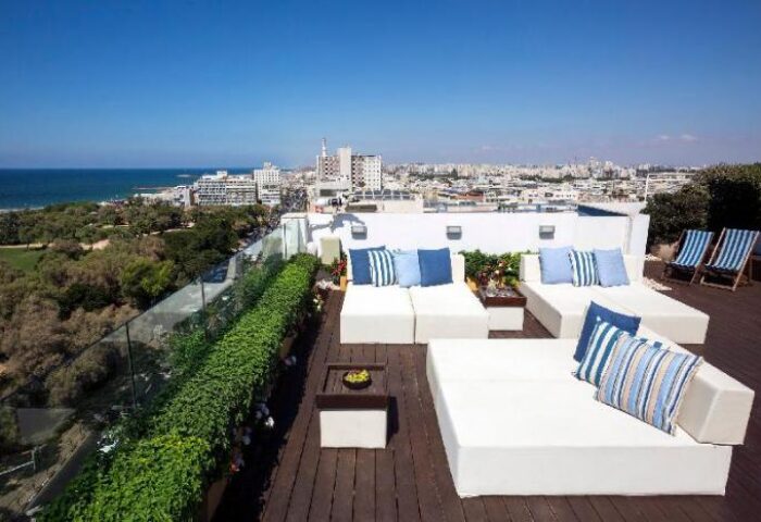 Melody Hotel, an Atlas Boutique Hotel rooftop terrace. Gay-friendly hotel with ocean view. Lounge chairs and city skyline in Tel Aviv.