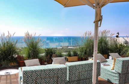Rooftop view at Melody Hotel, an Atlas Boutique Hotel. Gay-friendly hotel with ocean view, lounge chairs, plants and umbrella.