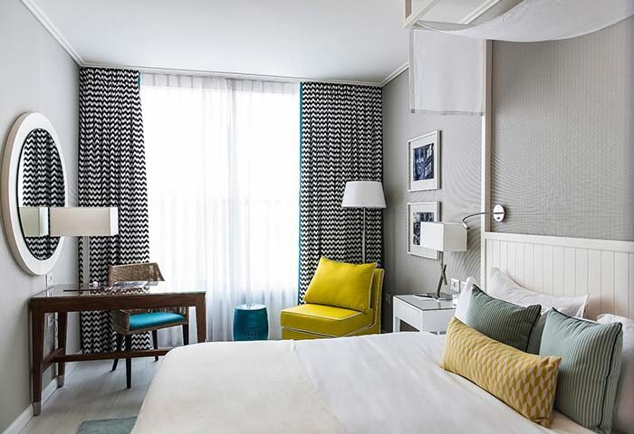 Melody Hotel, an Atlas Boutique Hotel room. Gay-friendly hotel room with a desk, bed, chair, and patterned curtains. Modern design.