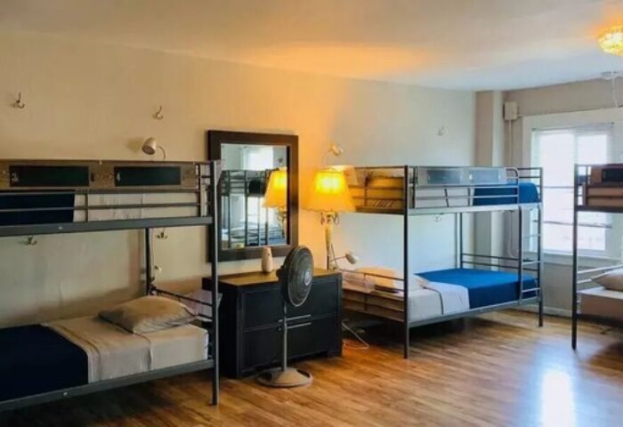 Dorm room at Melrose Hostel Adults Only, a gay-friendly hotel. Bunk beds, lamps, and a fan. Clean, simple, and inviting.