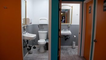 Melrose Hostel Adults Only gay-friendly hotel bathroom. Restrooms feature modern fixtures, clean design, and doors with male symbols.