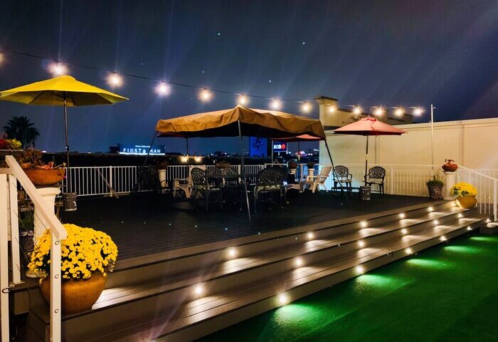 Melrose Hostel Adults Only gay-friendly hotel rooftop at night. Outdoor seating, umbrellas, string lights, and city views. Gay travel.