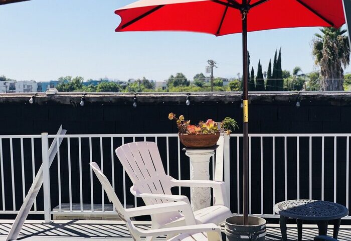 Melrose Hostel Adults Only gay-friendly hotel patio. Red umbrella, white chairs, and city views. Relaxing space for gay travelers.