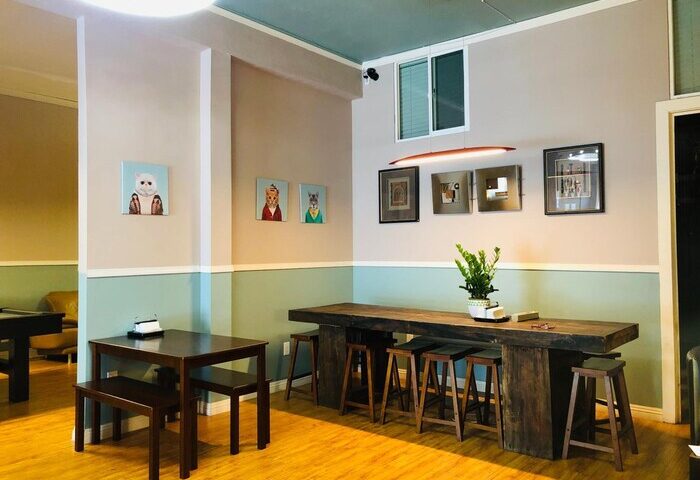 Melrose Hostel Adults Only interior. Gay-friendly hotel common area with tables, stools, and wall art. Relaxing space.