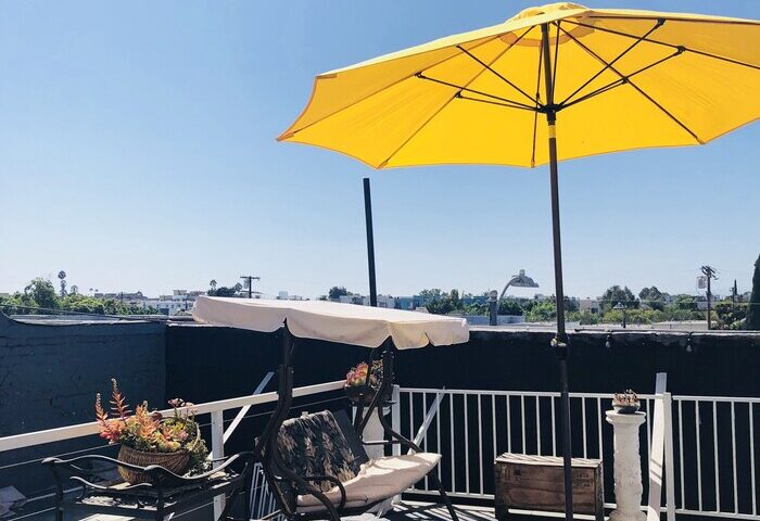Melrose Hostel Adults Only gay-friendly hotel rooftop patio. Yellow umbrella, swing, string lights, and city views. Ideal for gay men travel.