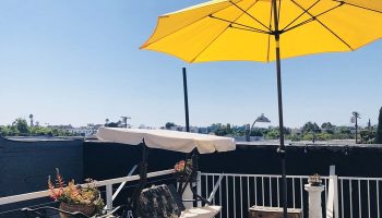 Melrose Hostel Adults Only gay-friendly hotel rooftop patio. Yellow umbrella, swing, string lights, and city views. Ideal for gay men travel.